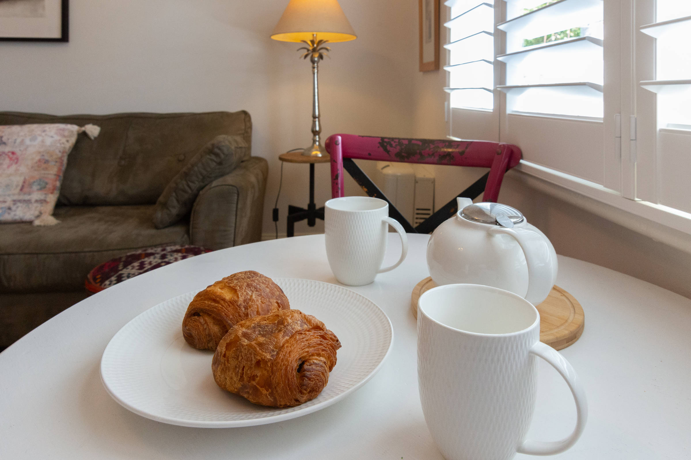 Close up of table setting with croissants and teapots and mugs. Photo: Oliver Berlin.