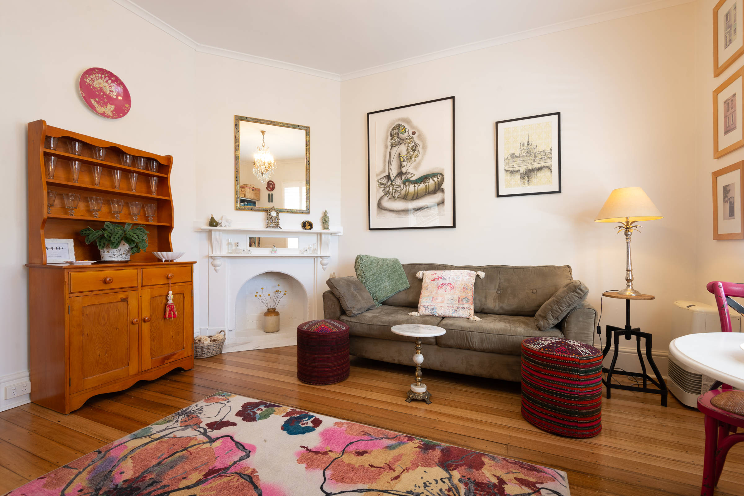 Sitting room with kitchen dresser, large floral rug, couch. artwork, lamp. Photo: Oliver Berlin.