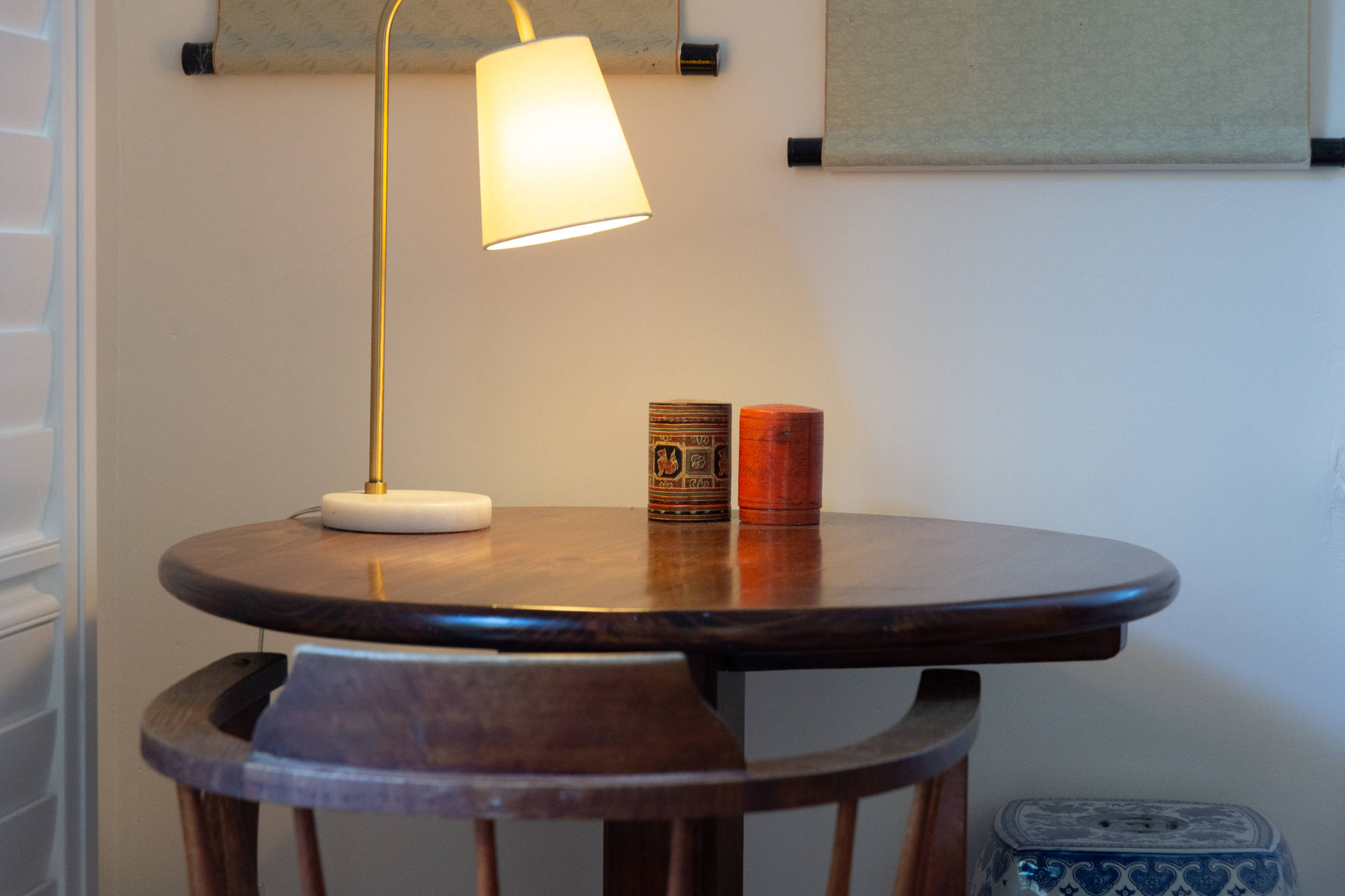 Small round table with lamp and large fish paintings on the wall. Photo: Oliver Berlin.
